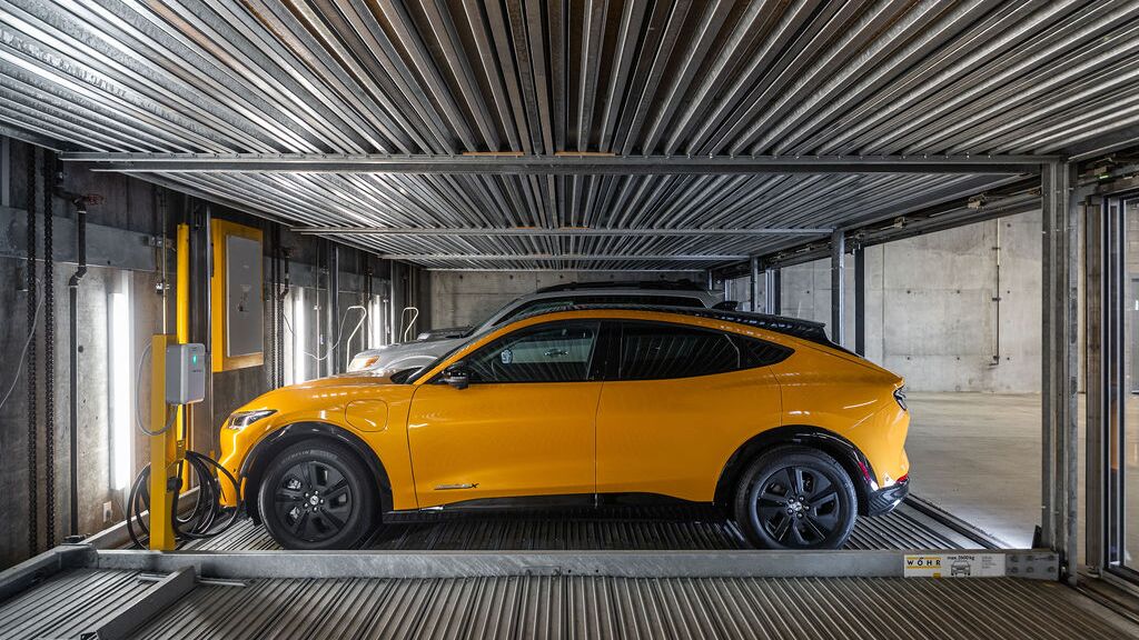 Bilden visar en bil på en plattform i ett automatiserat parkeringssystem i ett modernt underjordiskt garage.