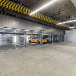 Bilden visar ett modernt underjordiskt garage med flera inglasade parkeringsplatser i ett parkeringssystem.