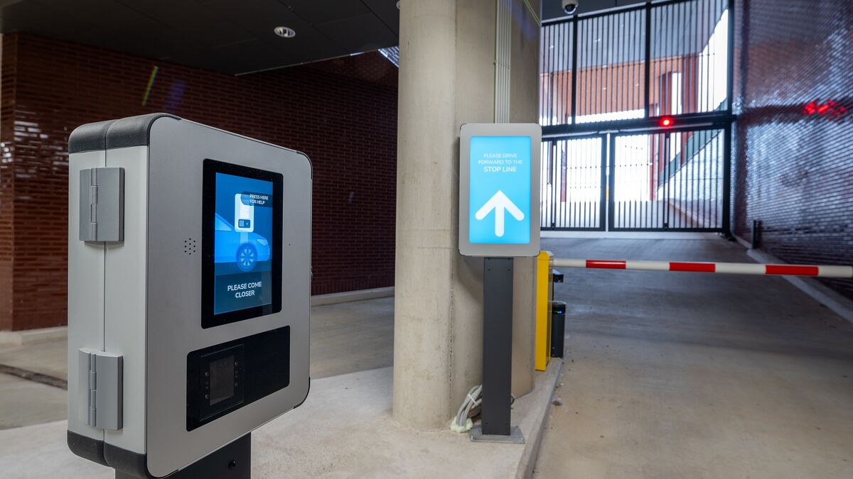 Utfart från ett modernt parkeringssystem med åtkomstterminal, digitalt informationssystem för förare och automatisk bom.